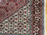 un gros plan d'un tapis oriental posé sur un parquet