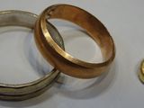 two rings and a gold pendant on a white surface
