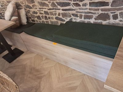 un banc avec un coussin, à côté d'une table sur laquelle se trouve un ours en peluche