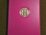 a close up of a pink book with a gold medallion on it