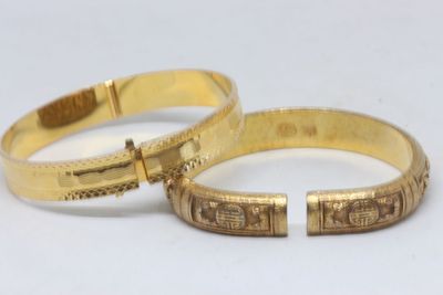 deux bracelets rigides en or ornés de motifs gravés sur un fond blanc