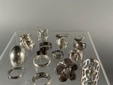 a lot of silver rings on display on a clear shelf