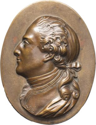 un gros plan sur un médaillon en bronze représentant un homme aux cheveux longs
