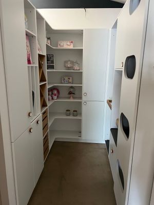 un petit dressing avec des armoires et des étagères blanches