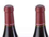 three bottles of wine are lined up in a row on a white surface