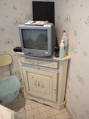 une petite télévision posée sur un meuble, dans un coin de la pièce