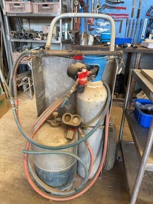 une bonbonne de propane à laquelle est raccordé un tuyau, dans un garage