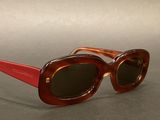 brown and red sunglasses on a table with a gray background