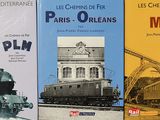 trois livres posés sur une table, avec une tour horloge en arrière-plan