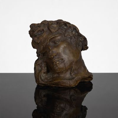 une sculpture en bronze représentant une tête de femme sur un fond noir