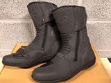 pair of black motorcycle boots sitting on a box in front of a brick wall