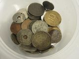 un bol blanc rempli d'une multitude de pièces de monnaie différentes