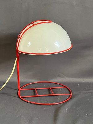 une lampe posée sur un pied, sur un fond gris