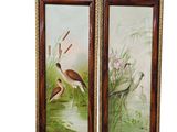 two framed paintings of birds in a pond with reeds and flowers