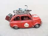 a red toy car with luggage on top of it