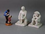 three figurines of a man and a woman sitting on a bench