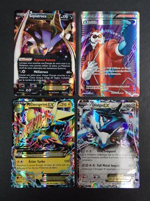 quatre cartes Pokémon différentes posées sur une table avec un fond noir