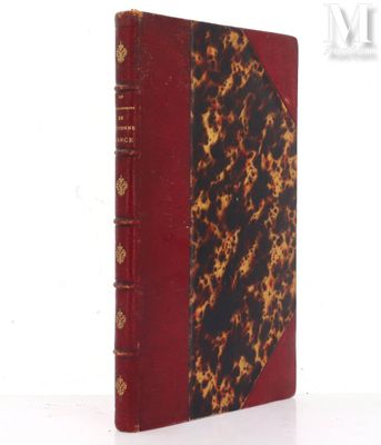 un vieux livre à la couverture rouge posé sur une table blanche