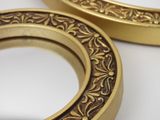 two gold colored metal rings with designs on them on a white surface