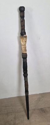 a wooden stick with a carved handle on a wooden table