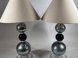 pair of glass lamps with shades on each of them on a table