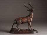 bronze sculpture of a stag standing on a rock on a gray background