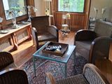 un salon avec des fauteuils en osier et une table basse en verre