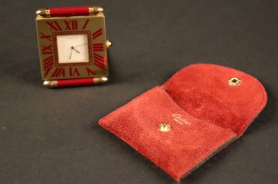 un petit étui rouge et une petite horloge rouge posés sur une surface noire
