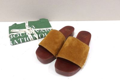 brown sued slippers with brown soles on a white surface
