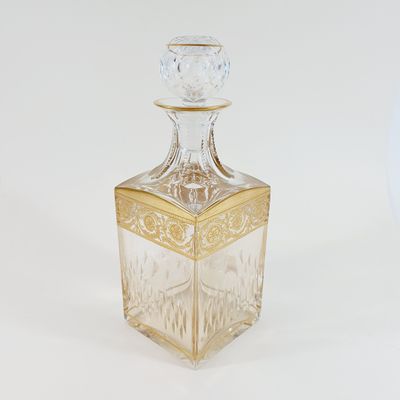 a clear glass bottle with a gold decoration on it