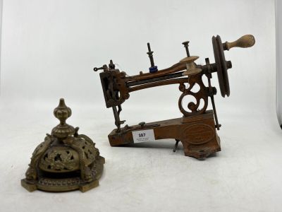 une petite machine à coudre posée sur une table, à côté d'une cloche