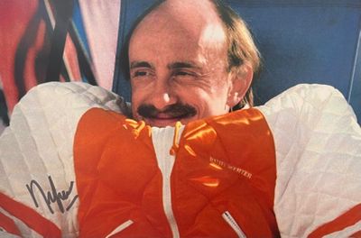 un homme portant une veste orange et blanche et arborant une moustache