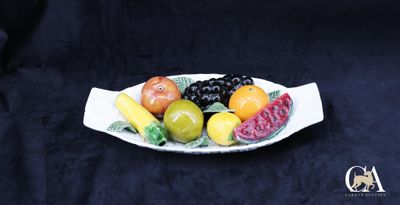 une assiette blanche avec des fruits dessus, sur fond noir