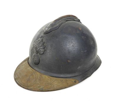 un vieux casque repose sur une surface blanche, surmonté d'une casquette marron