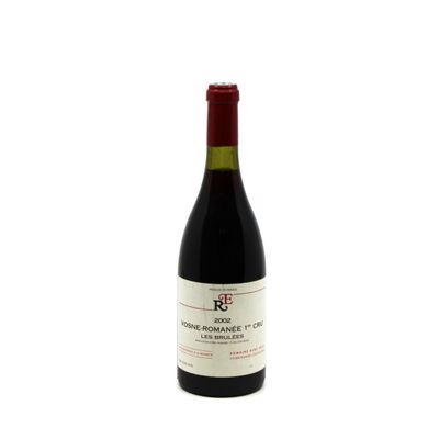 the bottle of red wine is sitting on a white surface