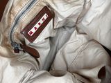 a brown bag with a brown handle sitting on a bed
