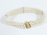 a close up of a white pearl bracelet with a gold clasp