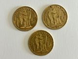 three gold coins sitting next to each other on a white surface