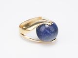 gros plan d'une bague en or avec une pierre bleue