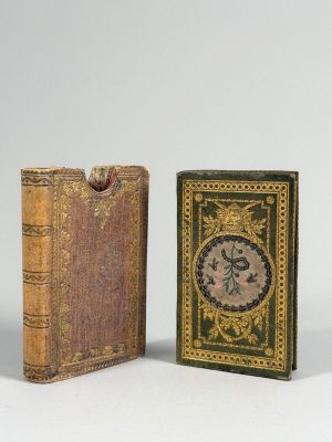 deux livres miniatures posés l'un sur l'autre sur une surface blanche