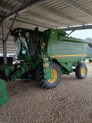 un gros tracteur vert garé sous une structure métallique
