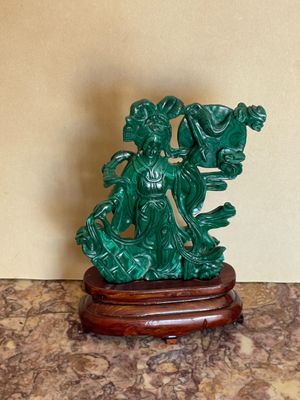 une statue représentant une femme tenant un panier de fleurs posé sur une table