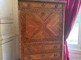 une commode dans une pièce où est accroché un tableau au mur