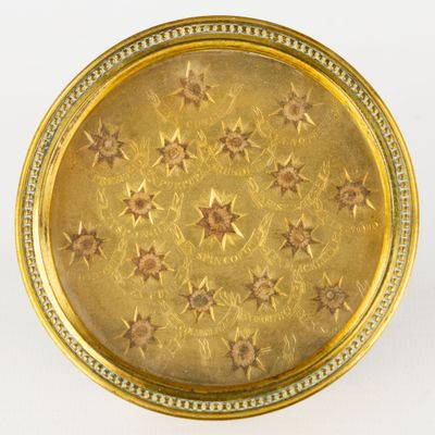 une assiette ancienne dorée, ornée d'étoiles sur un fond blanc
