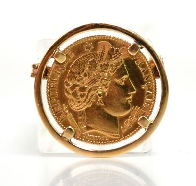 une image représentant une pièce d'or dans un support en verre posé sur une surface blanche