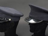 pair of police hats on mannequin heads on a black background