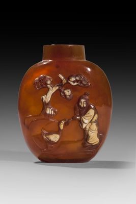 un vase en verre orange sur lequel est représenté un homme et une femme dans un paysage