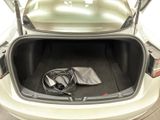 the trunk of a white car with a power cord in it