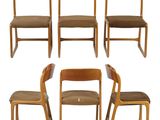 six wooden chairs with brown upholstered seats and a white background