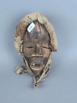 une image représentant un masque en bois sur lequel est accrochée une étiquette